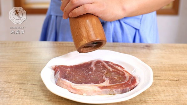在牛排上洒上橄榄油，再沾满盐和胡椒粉